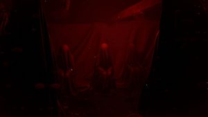 figures in dark red room in where dolls hang